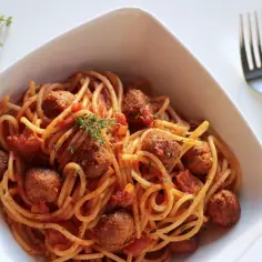 Pyszne spaghetti z klopsikami w sosie pomidorowym, doprawione ziołami. Idealne danie dla miłośników włoskich smaków.