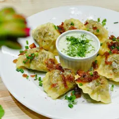 Pyszne pierogi ruskie z cebulką i śmietaną, posypane szczypiorkiem.
