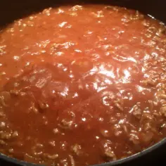 Gotowy do podania sos do spaghetti, z mielonym mięsem i pomidorami, gotujący się w garnku. Idealny przepis na to, jak zrobić sos do spaghetti.